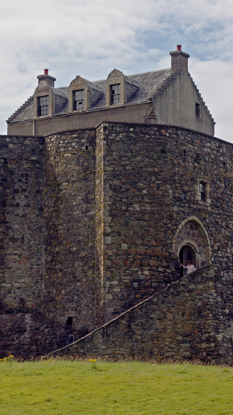 Brown Brick Building on Green Grass Field Under White Clouds During Daytime. Wallpaper in 750x1334 Resolution