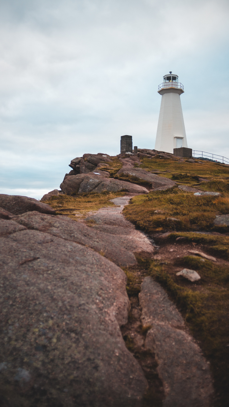 Weißer Und Schwarzer Leuchtturm Auf Braunem Felsigem Hügel Unter Weißem Bewölktem Himmel Tagsüber. Wallpaper in 750x1334 Resolution