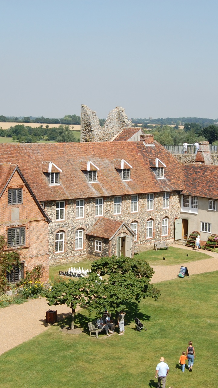 La Gente Caminando Sobre el Campo de Hierba Verde Cerca Del Edificio de Ladrillo Marrón Durante el Día. Wallpaper in 720x1280 Resolution