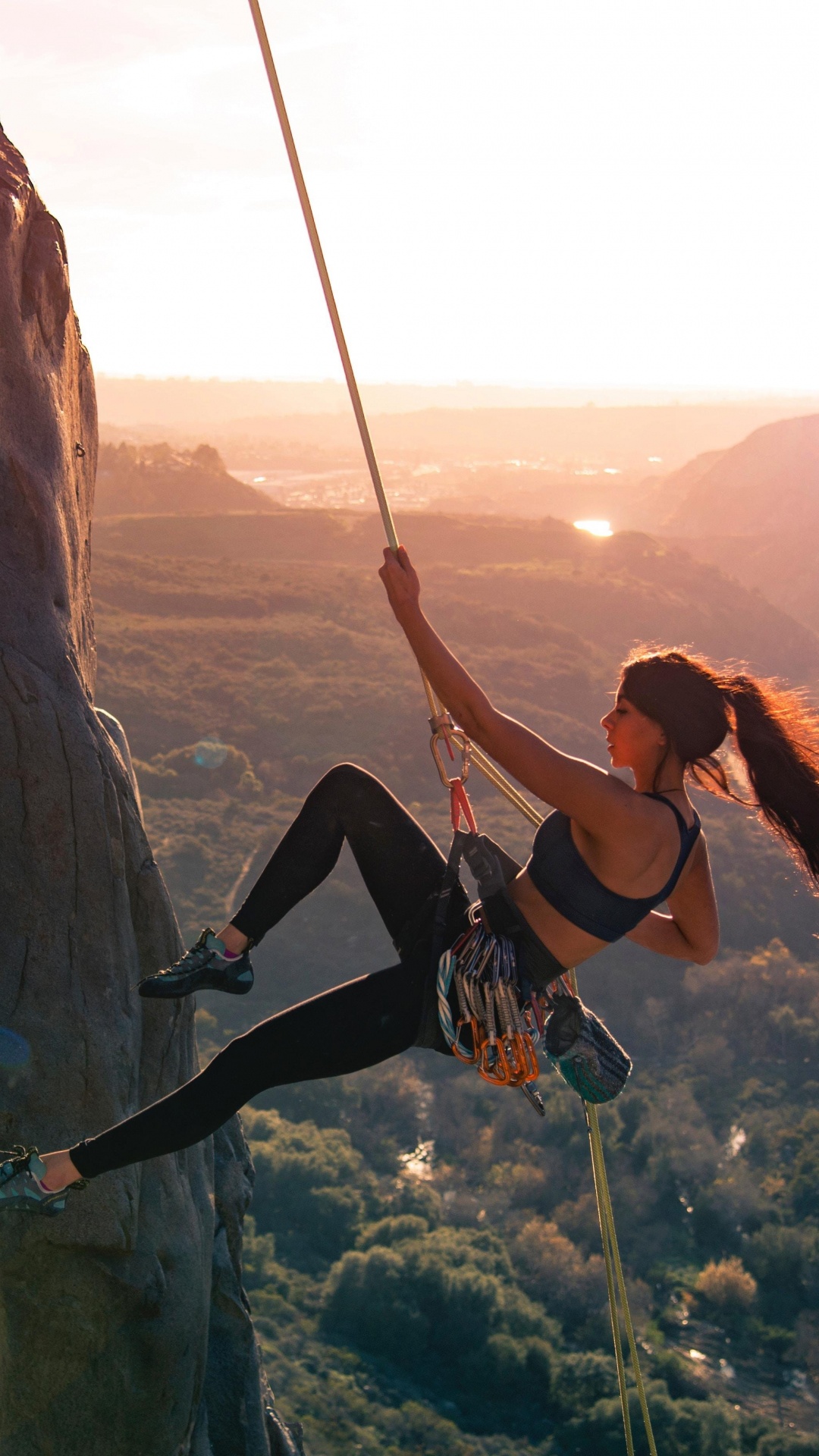Woman in Black Tank Top and Black Pants Climbing on Brown Rock Formation During Daytime. Wallpaper in 1080x1920 Resolution