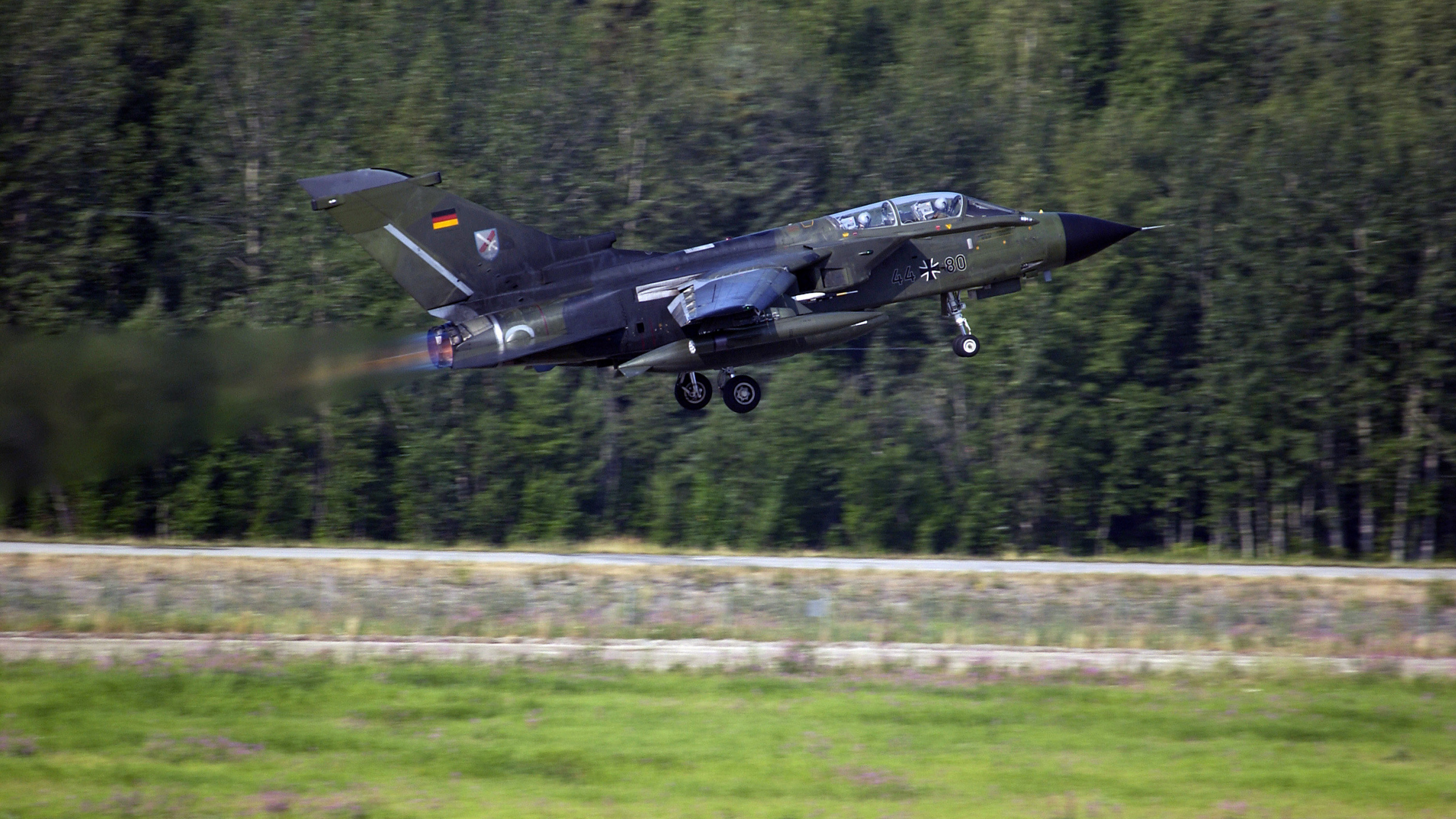 Black Jet Plane Flying Over Green Grass Field During Daytime. Wallpaper in 2560x1440 Resolution