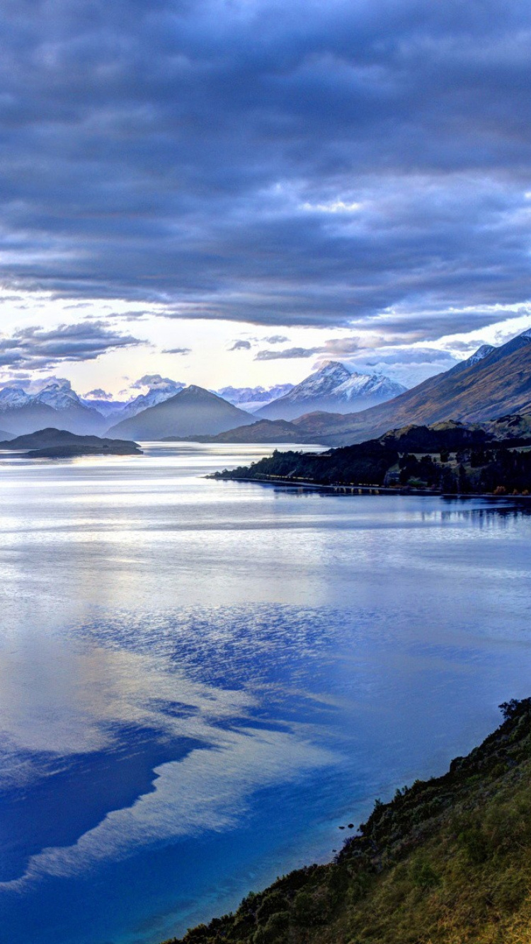 Lake in The Middle of Mountains Under White Clouds and Blue Sky. Wallpaper in 750x1334 Resolution
