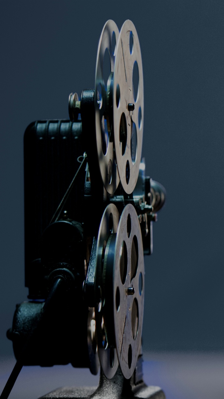 Man in Black Jacket Standing Beside Blue and Yellow Round Wall Decor. Wallpaper in 720x1280 Resolution