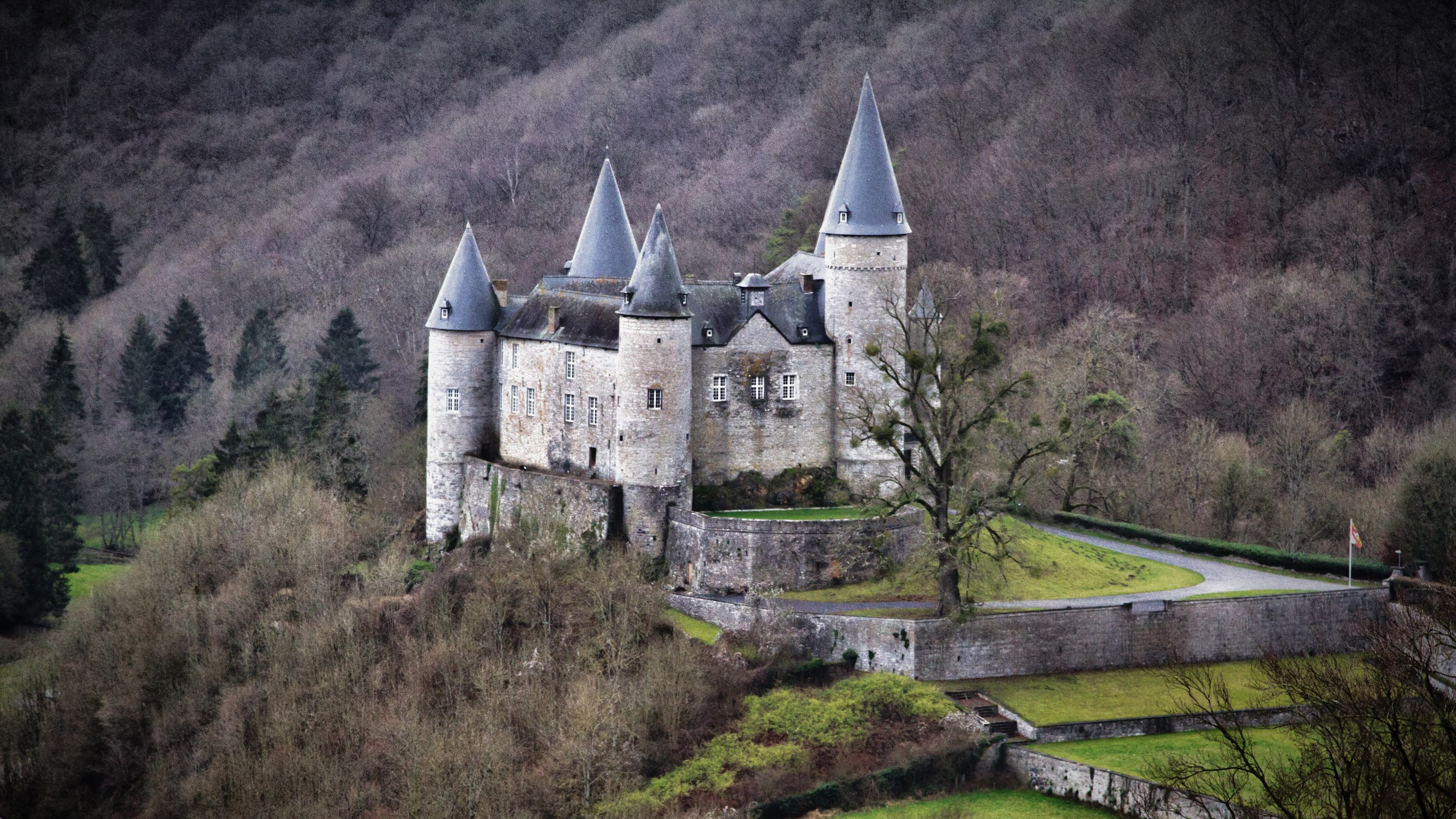 Grey Concrete Castle on Green Grass Field Near Mountain During Daytime. Wallpaper in 2560x1440 Resolution
