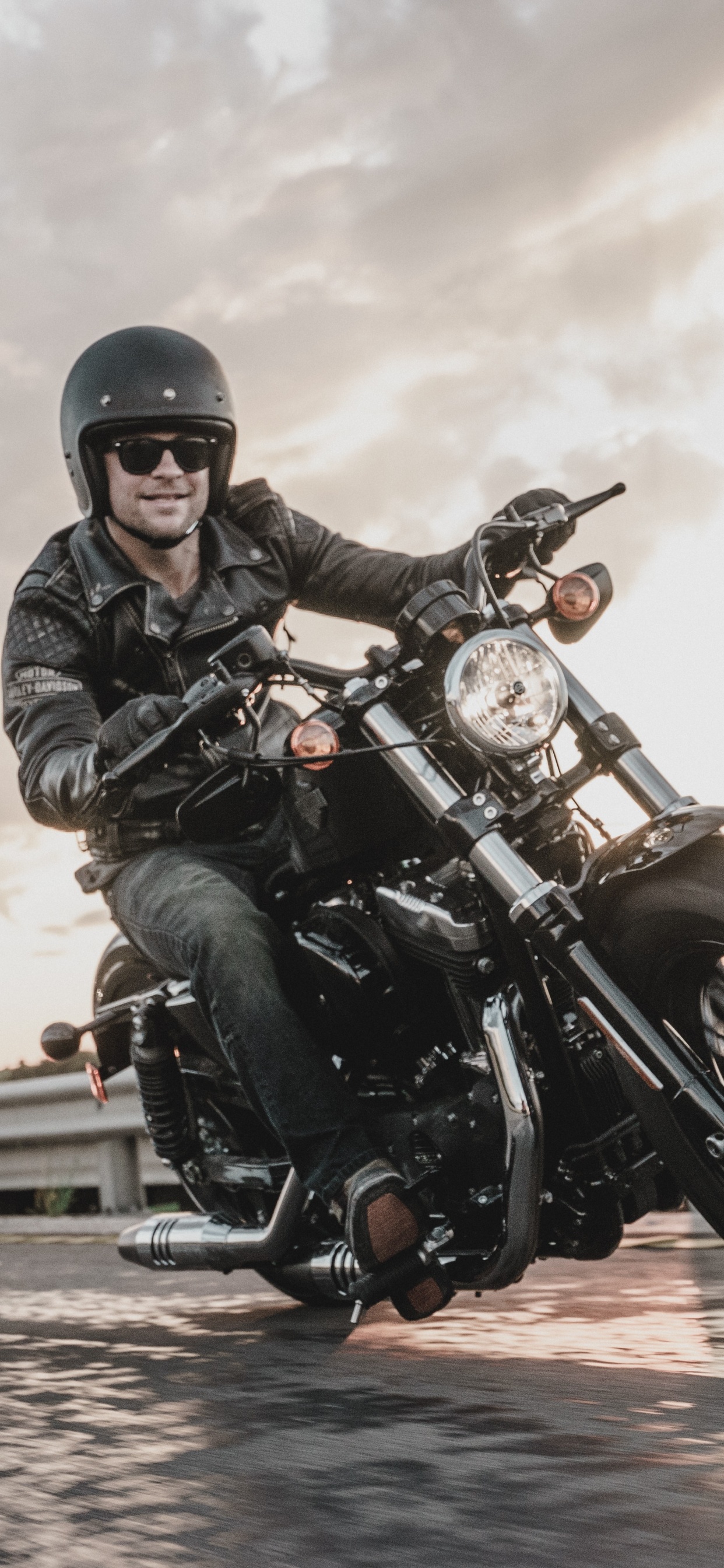 Man in Black Leather Jacket Riding Motorcycle. Wallpaper in 1242x2688 Resolution