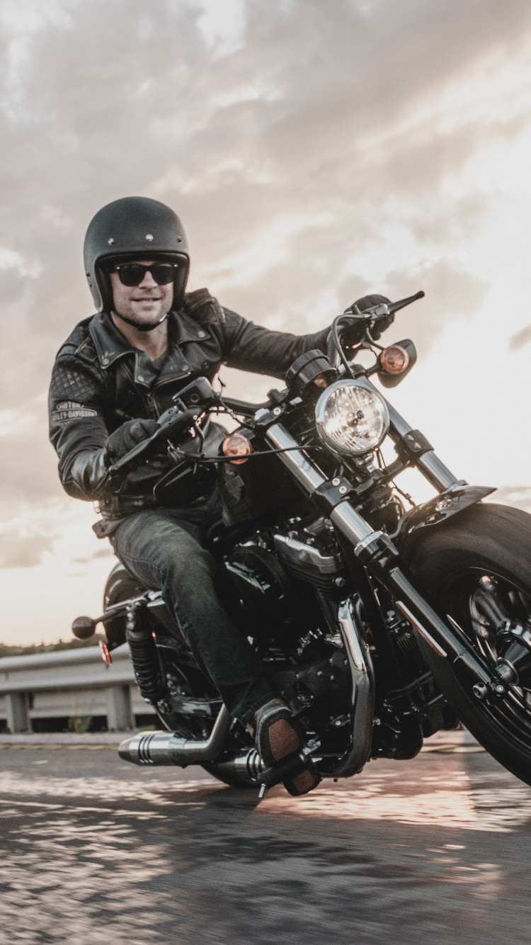 Man in Black Leather Jacket Riding Motorcycle. Wallpaper in 750x1334 Resolution