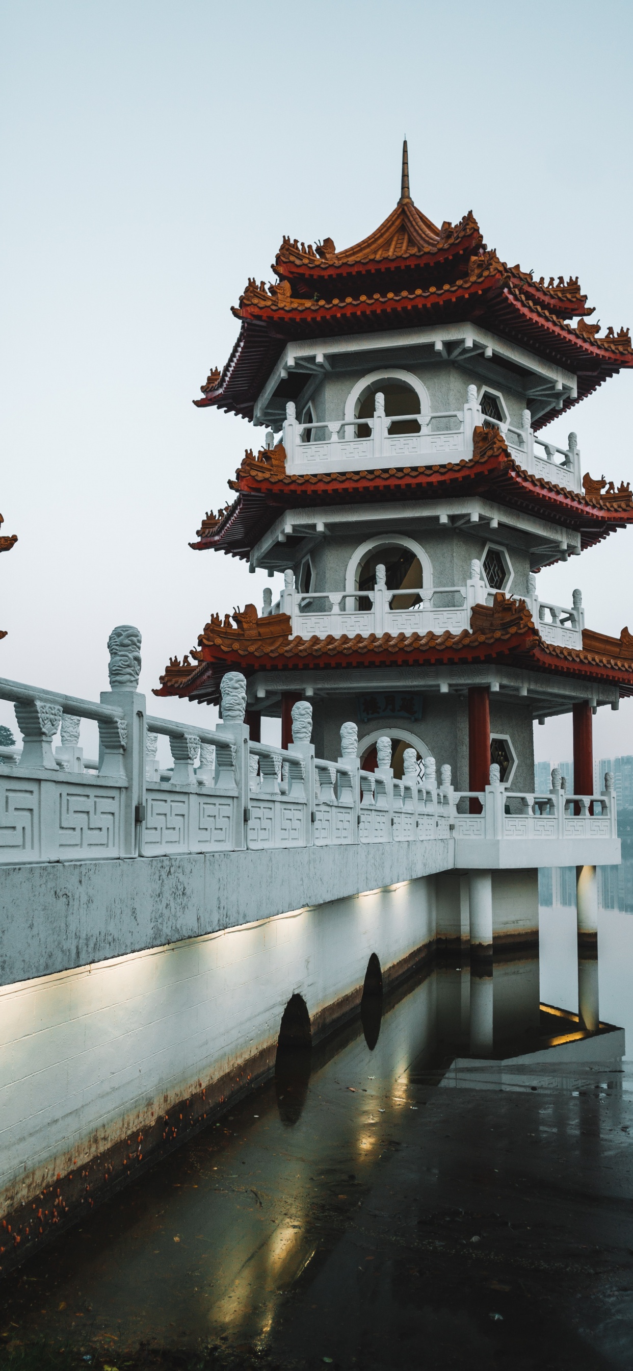 White and Red Concrete Building Near Body of Water During Daytime. Wallpaper in 1242x2688 Resolution