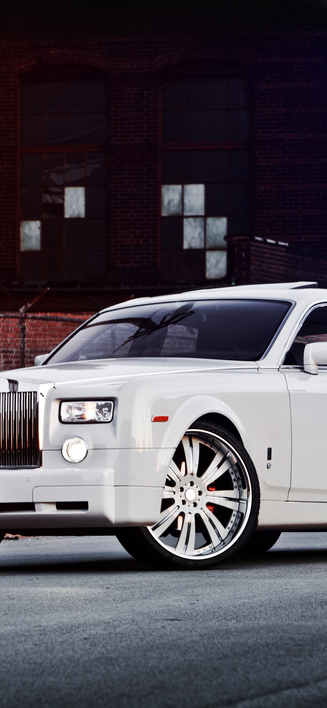 White Suv Parked Beside Brown Brick Building. Wallpaper in 1125x2436 Resolution