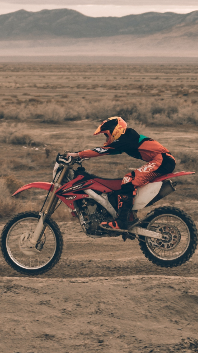 Hombre de Chaqueta Roja Montando Motocross Dirt Bike en Campo Marrón Durante el Día. Wallpaper in 750x1334 Resolution