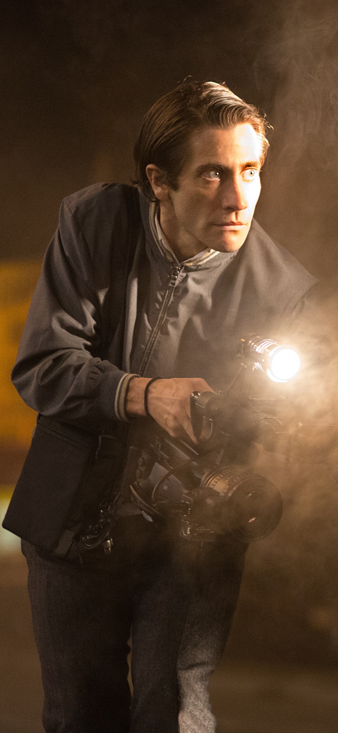 Man in Black Leather Jacket Holding a Light. Wallpaper in 1125x2436 Resolution