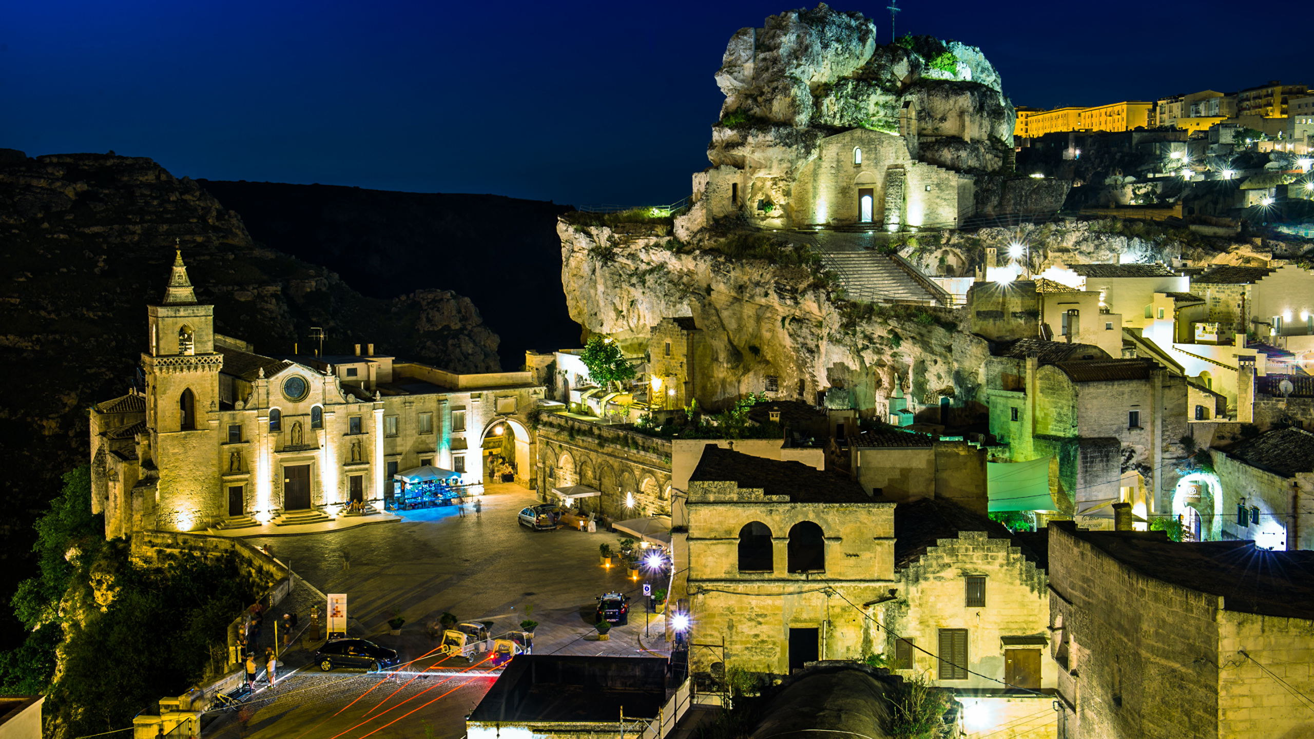 Brown Concrete Building Near Mountain During Night Time. Wallpaper in 2560x1440 Resolution