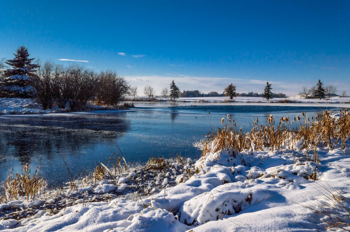 Campo Cubierto de Nieve Cerca Del Cuerpo de Agua Bajo un Cielo Azul Durante el Día. Wallpaper in 2048x1355 Resolution