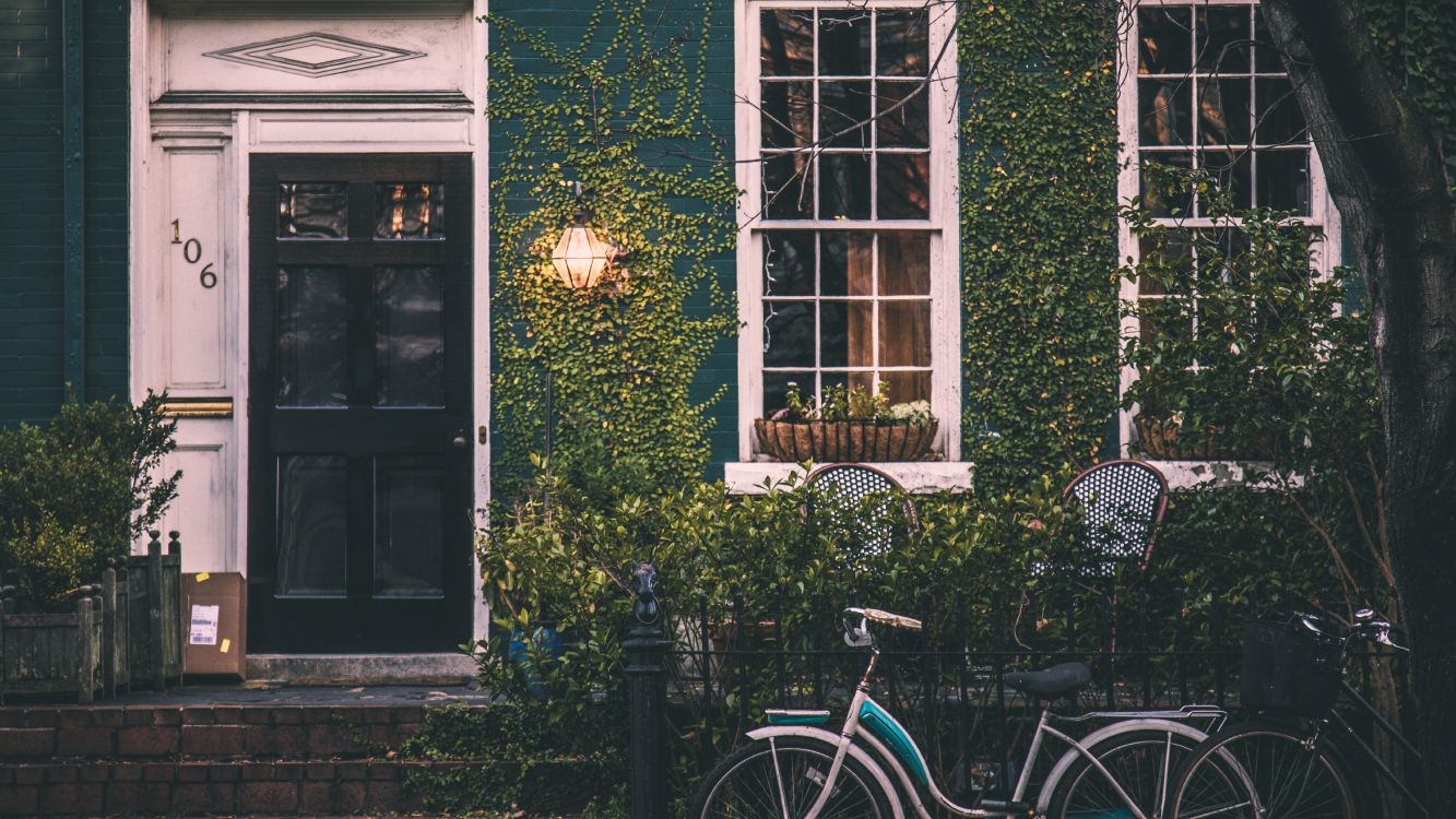 blue city bike parked beside green wooden window