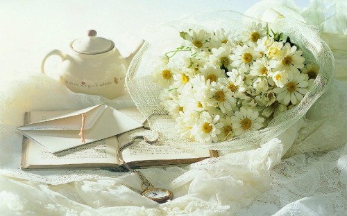 Image white flowers on white table napkin beside silver fork and bread knife