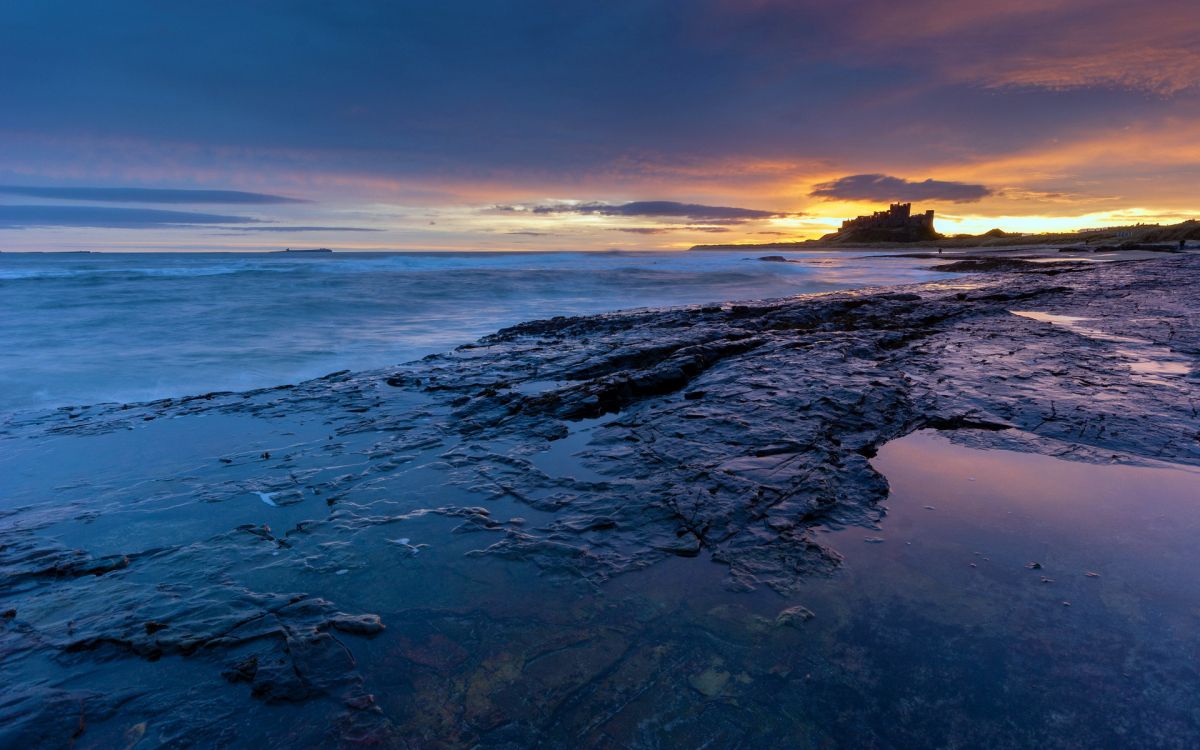 ocean waves crashing on shore during sunset