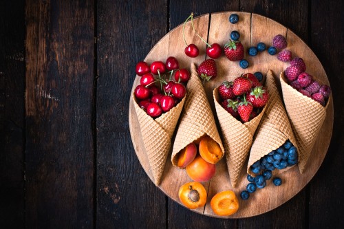 Image red and blue berries on brown wooden bowl