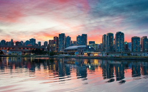 Image city skyline across body of water during sunset