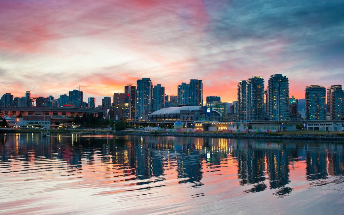 city skyline across body of water during sunset