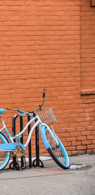 Image blue city bike parked beside brown brick wall