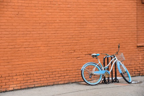 Image blue city bike parked beside brown brick wall