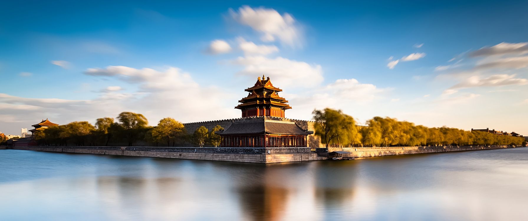 brown and black temple near green trees and river under blue sky during daytime