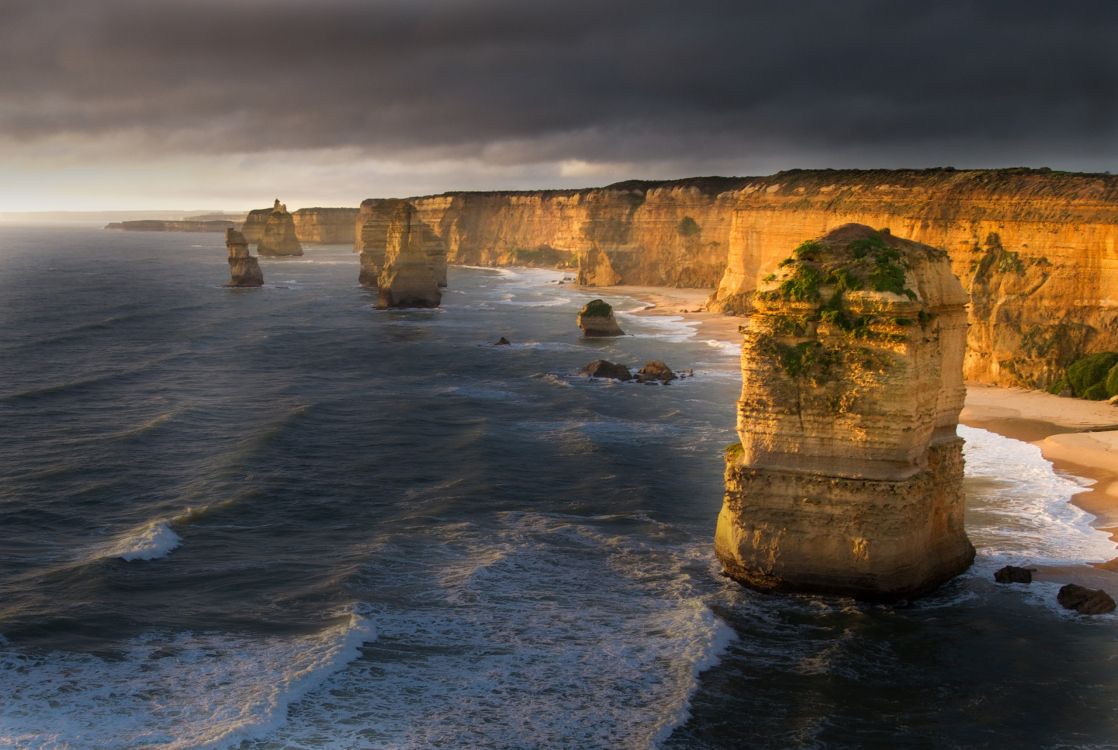 Montaña Rocosa Gris Junto al Cuerpo de Agua Durante el Día. Wallpaper in 2560x1717 Resolution