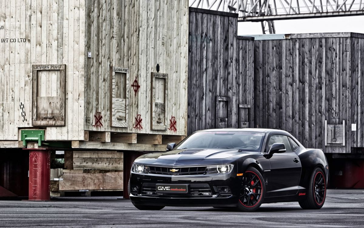 black car parked beside brown wooden wall