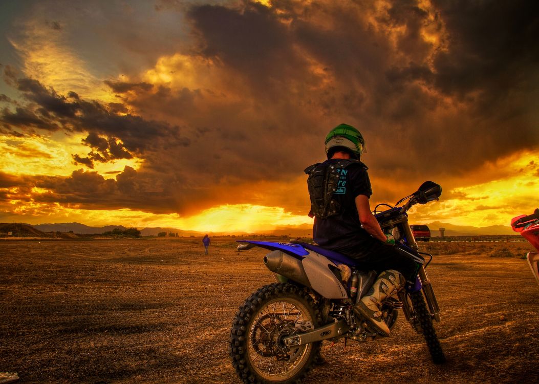 man riding motorcycle on brown field during sunset