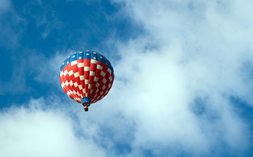 Image red blue and yellow hot air balloon in mid air under white clouds and blue sky