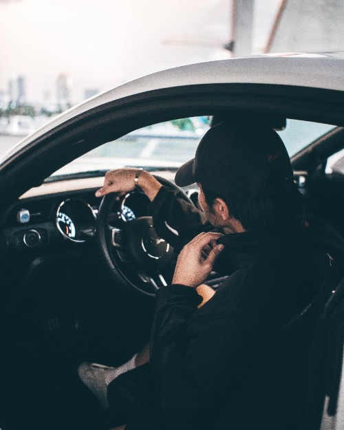 Image man in black jacket driving car during daytime