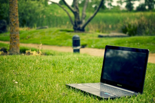 Image black and gray laptop computer on green grass during daytime