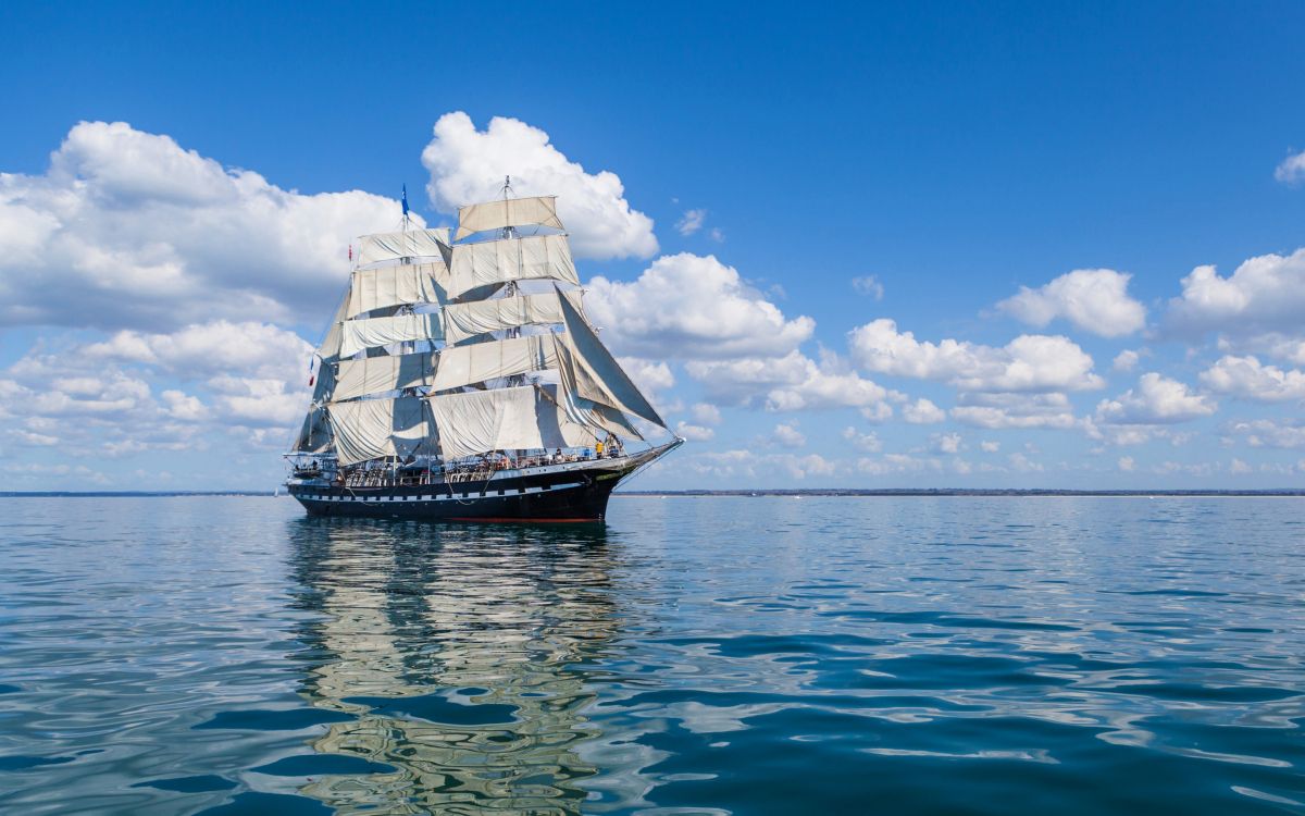 brown and white sail ship on sea under blue sky during daytime