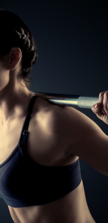 Image woman in black sports bra holding gray metal bar