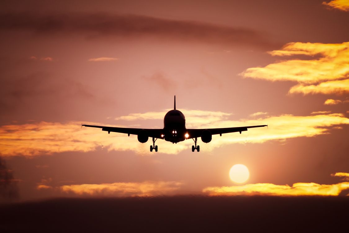 airplane flying in the sky during sunset