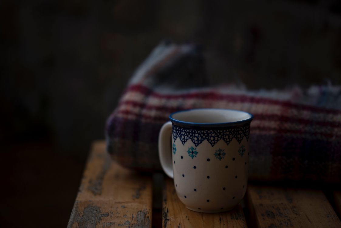 white and blue floral ceramic mug on brown wooden table