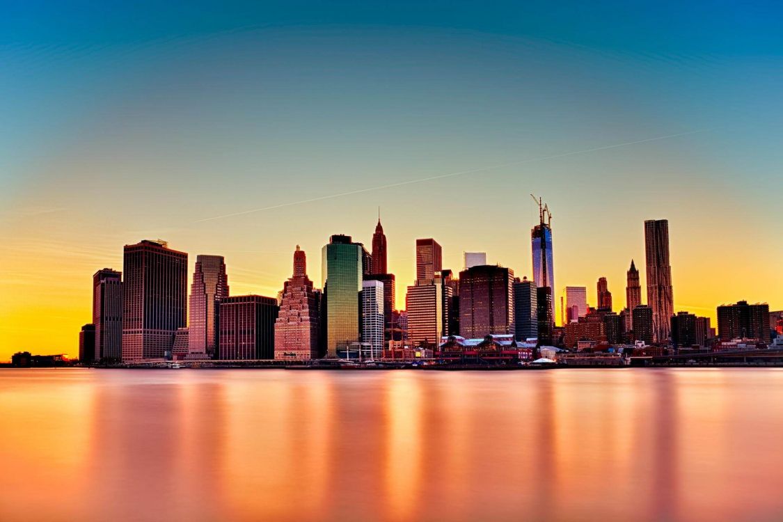 city skyline across body of water during night time