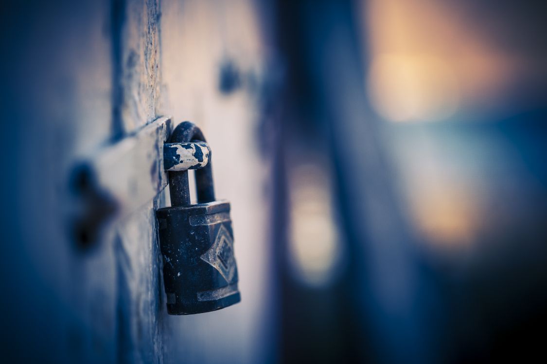 black padlock on blue metal fence