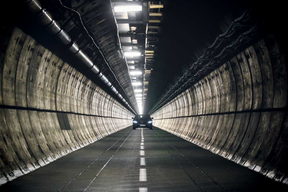 man in black jacket walking on tunnel