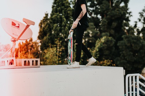 Image man in black pants and black jacket riding skateboard