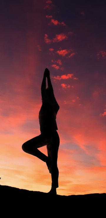 Image silhouette of woman standing on rock during sunset