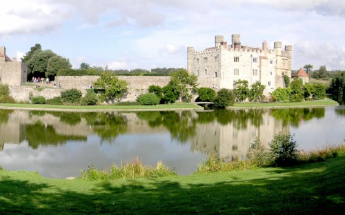 Image gray concrete building near green grass field and lake under white clouds and blue sky during