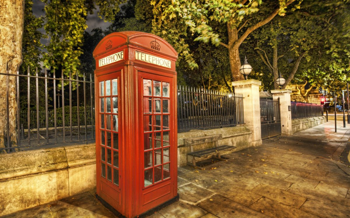 red telephone booth near green trees during daytime