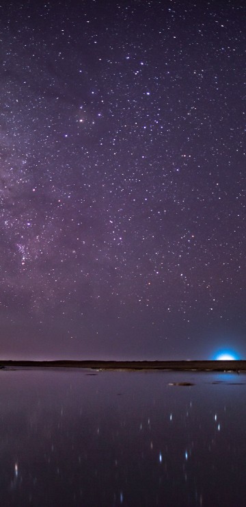 Image brown rock formation on body of water under starry night