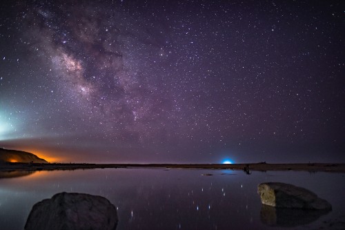 Image brown rock formation on body of water under starry night