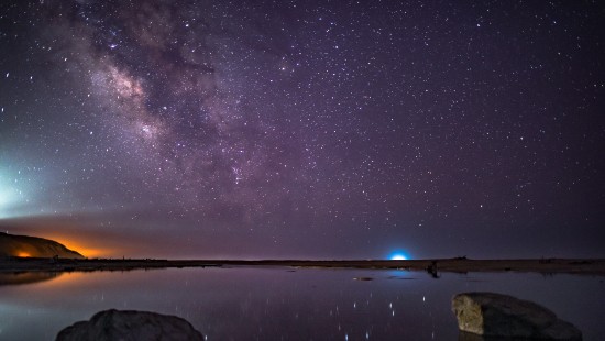 Image brown rock formation on body of water under starry night