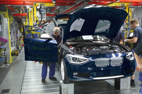 Image woman in blue sleeveless dress standing beside black bmw car