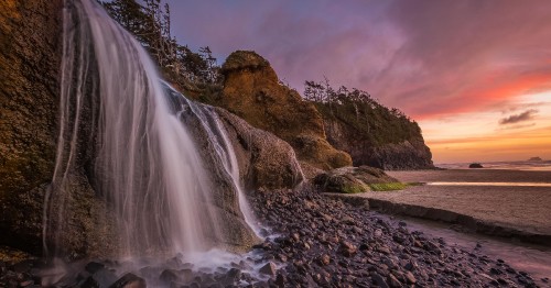 Image water falls on brown rocky mountain under gray cloudy sky