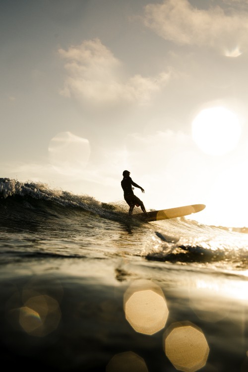 Image silhouette of man holding surfboard on water during daytime