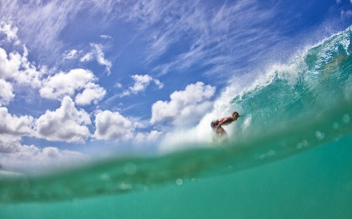 Image person surfing on sea waves under blue and white cloudy sky during daytime