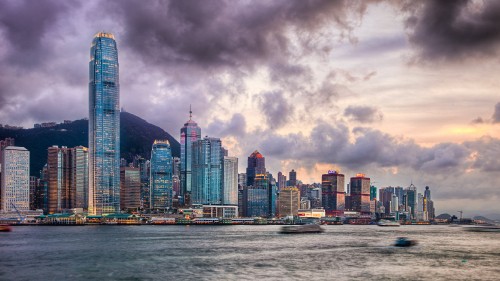 Image city skyline across body of water under cloudy sky during daytime